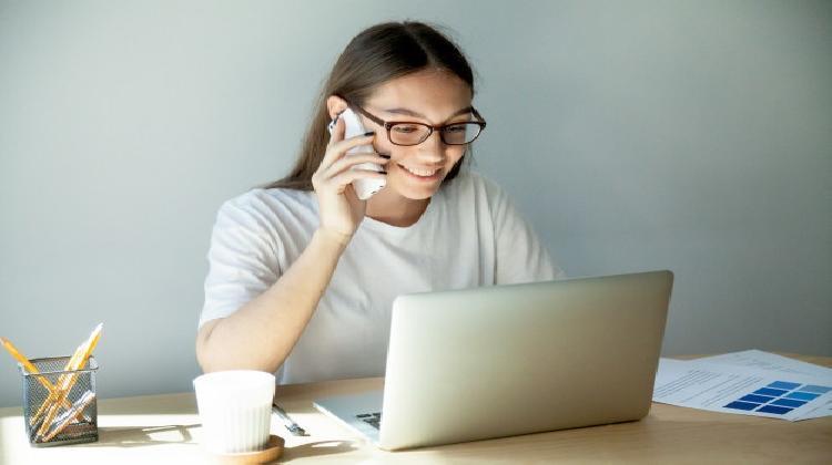 mujer-milenaria-gafas-hablando-celular-usando-lapt